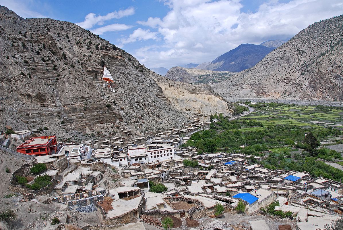 101 Marpha View Towards North After lunch in Jomsom, it took us only an hour to trek along the river bank much of the way to Marpha. Marpha (2680m) is situated in a little in a side valley and is protected from the strong winds, which blow in the middle of the river valley. The rooftops are bordered by neat stacks of firewood and provide a place where the women can work in the sun, drying and processing their produce. Everything in Marpha is clean and neat.